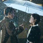 Couple standing under umbrella in the rain.