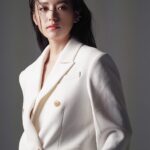 Woman in white blazer looking forward.