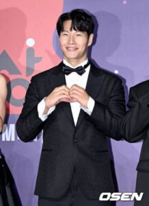 Man in tuxedo making heart gesture.