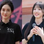 Two women smiling, holding items, wearing black shirts.