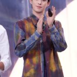 Person clapping, wearing colorful patterned shirt.