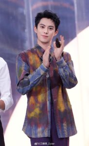 Person clapping, wearing colorful patterned shirt.