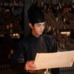 Man in historical attire reading ancient scroll.