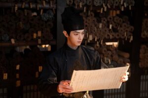 Man in historical attire reading ancient scroll.