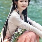 Woman in traditional attire by the water.