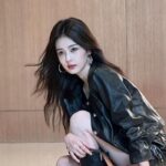 Woman in black jacket holding a bag.