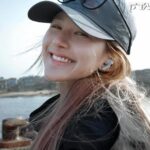 Smiling woman wearing cap by the water.