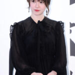 Woman in black dress at event.