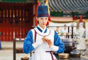 Person in traditional Korean attire, hands clasped.