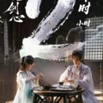 Period drama characters sitting at a table.