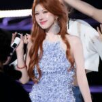 Woman in blue dress holding microphone on stage.