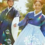 Couple in traditional attire with bubbles outdoors.