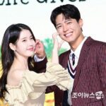 Two people smiling, touching each other's ears.