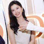 Smiling woman in elegant setting, white dress.