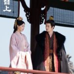 Period drama characters in traditional attire conversing.