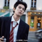 Person in suit holding camera on street.