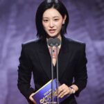 Woman in black suit holding an award.