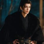 Person in black traditional robe, hands on hips